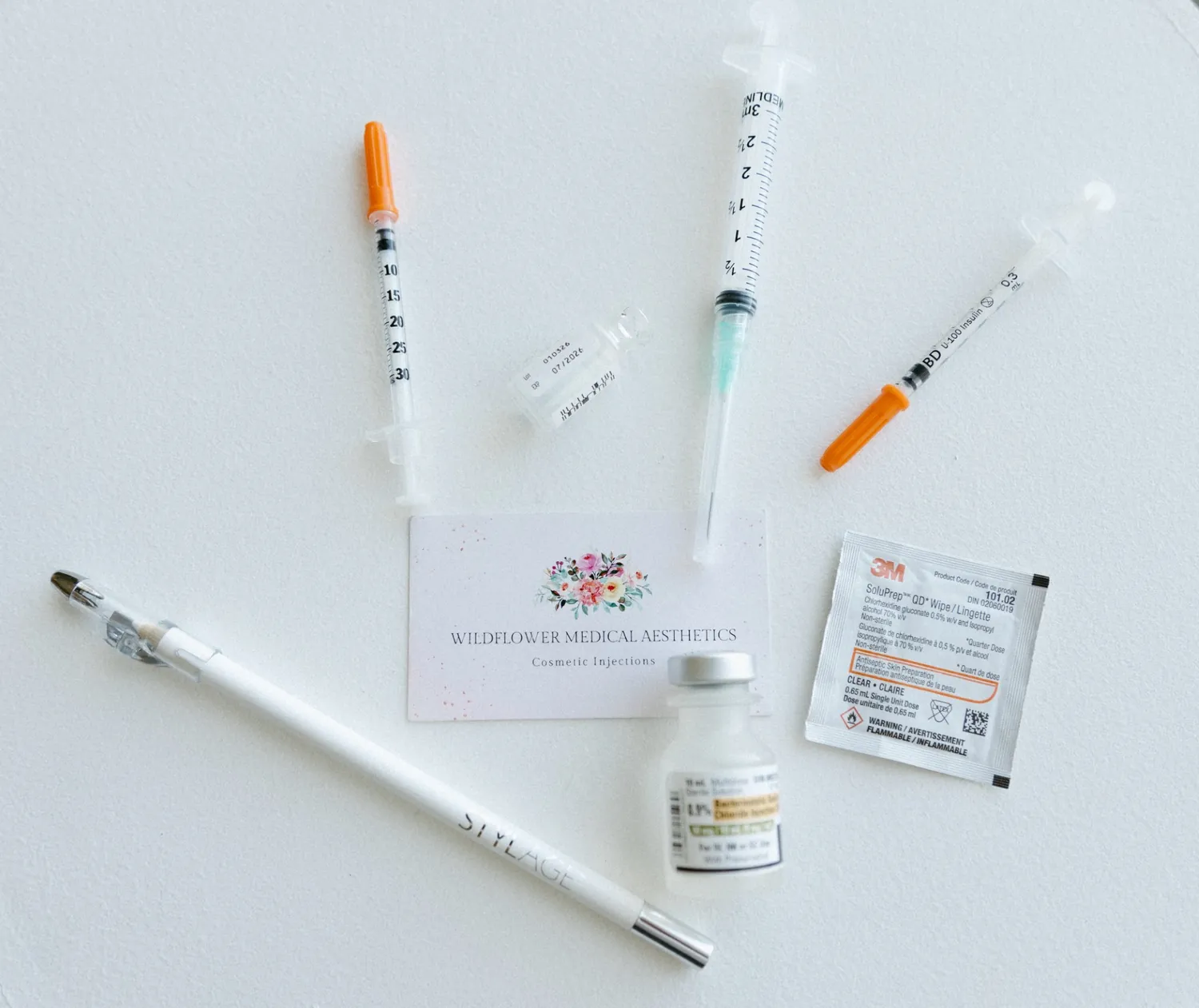 Syringes, a vial and a Wildflower business card laid out before treatment